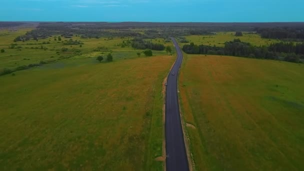 日没と高電圧線のフィールドの真ん中に田舎の車がほとんどなく、道路です。 — ストック動画