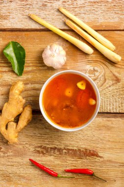 Geleneksel Tayland Tom Yam çorbası bir tabakta sarımsak ve limon, kaffir limonu, biber ve kiraz yanında..