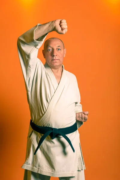 En karate man i vit kimono med svart bälte tränar. — Stockfoto