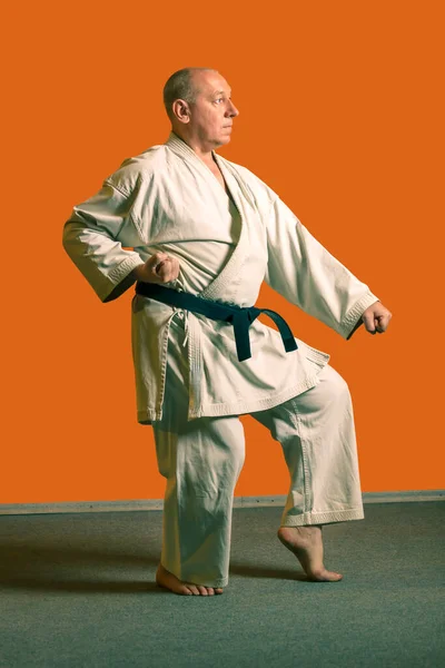 A karate man in a white kimono with a black belt performs kata getting ready for the competition. — Stock Photo, Image