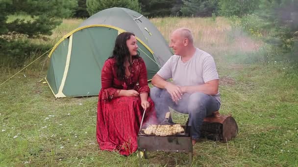 Familie paar man en vrouw zigeuners in de buurt van de tent grill vlees romantiek. — Stockvideo