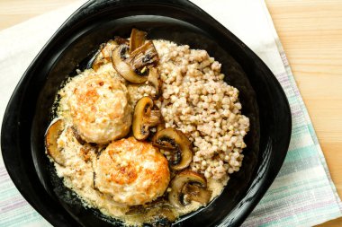 Kremalı soslu mantarlı tavuk köftesi ve siyah tabakta yeşil karabuğday..