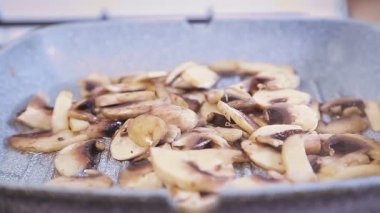 Bir kadının eli baharatlı tavada kızartılmış mantar serpiştirir.