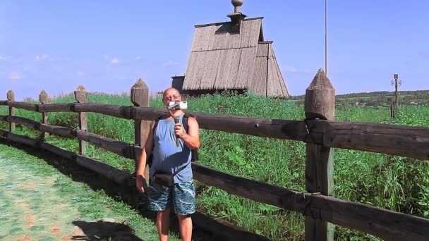 Een mannelijke blogger zendt uit vanaf de top van een berg en praat over een houten tempel.. — Stockvideo