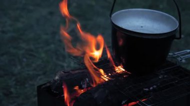 Alacakaranlıkta ateşte kapağı kaynamış bir kazan..