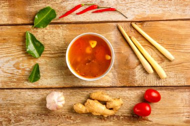 Geleneksel Tayland Tom Yam çorbası bir tabakta sarımsak ve limon, kaffir limonu, biber ve kiraz yanında..