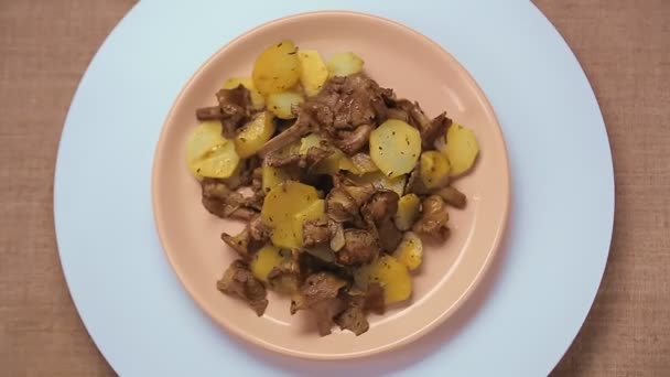 Fried potatoes with chanterelle mushrooms in a beige plate. — Stock Video