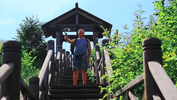 Un hombre bloguero de viajes cuenta un blog desde una escalera que conduce a la cima de la montaña . — Vídeo de stock