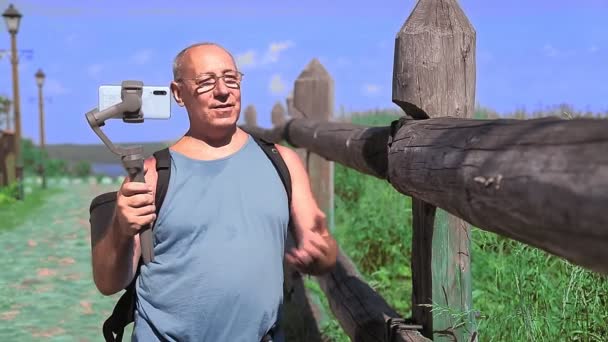 Un blogger masculino está transmitiendo desde la cima de una montaña con vistas al río . — Vídeo de stock