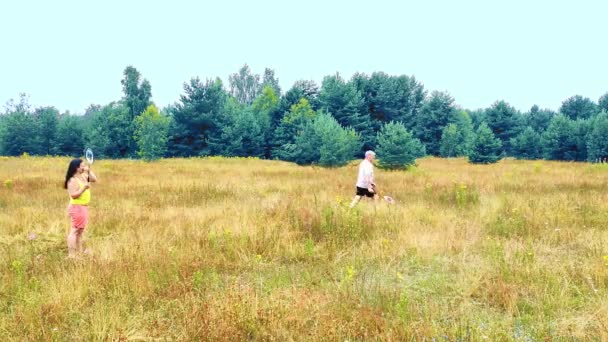 Un uomo e una donna in vacanza a giocare a badminton nel prato. Giri di tempo — Video Stock