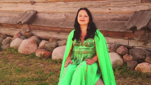 Uma mulher oriental em um traje de dança cobre seu rosto com um xale verde . — Vídeo de Stock