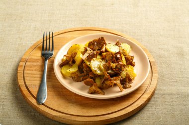 Yuvarlak bir sette keten masa örtüsünde larva mantarlı patates kızartması ve çatal..