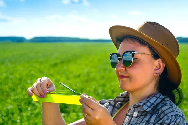 Güneş gözlüklü ve şapkalı bir tarımcı kadın ekinlerin parametrelerini ölçer.. — Stok fotoğraf