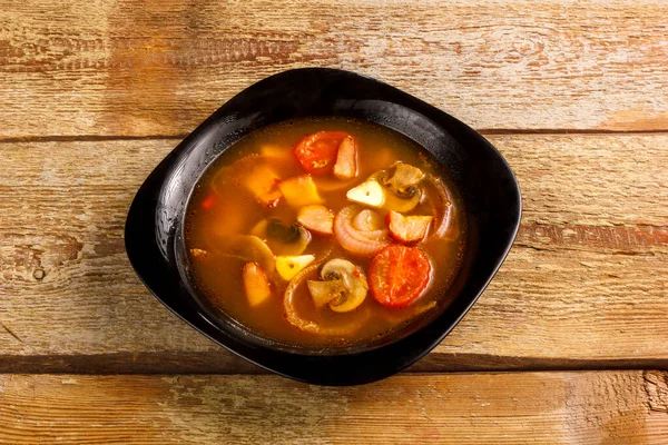 Traditionele Thaise Tom Yam soep in een zwarte plaat op een houten tafel. Kopieerruimte — Stockfoto