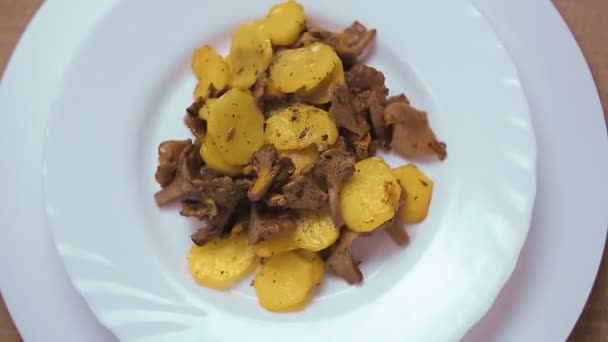 Fried potatoes with chanterelle mushrooms in a white plate. — Stock Video