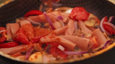 Bir kadının eli yumurtanın üzerine baharatlı sebzeler serpiştirir ve kömürün üzerinde durur..