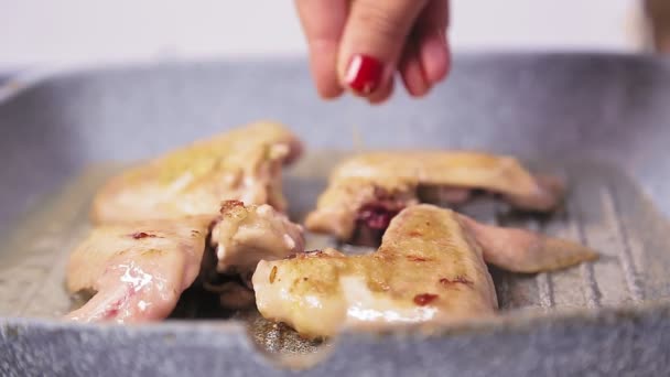 As pinças de grelha rodam as asas de frango na frigideira . — Vídeo de Stock