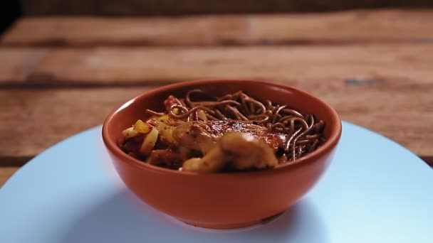 Nouilles soba au sarrasin avec légumes et ailes de poulet dans une assiette beige tourner en cercle. — Video