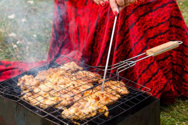 Zarif bir çingene kadın ızgara etin hazır olup olmadığını kontrol eder..