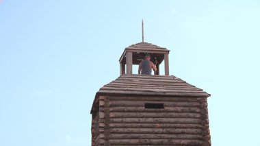 Bir erkek blogcu kaledeki gözlem güvertesinden telefonundan blog yazıyor.