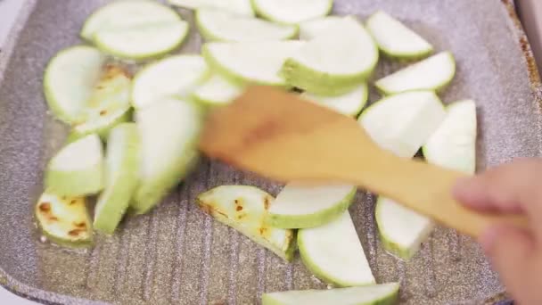 Una espátula de madera da vuelta al calabacín frito al aceite — Vídeos de Stock