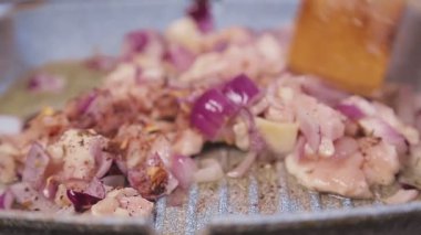Bir spatula tavuklu filetoyu tavada soğanla karıştırır..