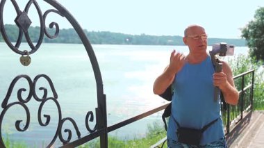 Seyahat hakkında cep telefonu olan bir erkek blogcu büyük bir nehrin setinden bahsediyor