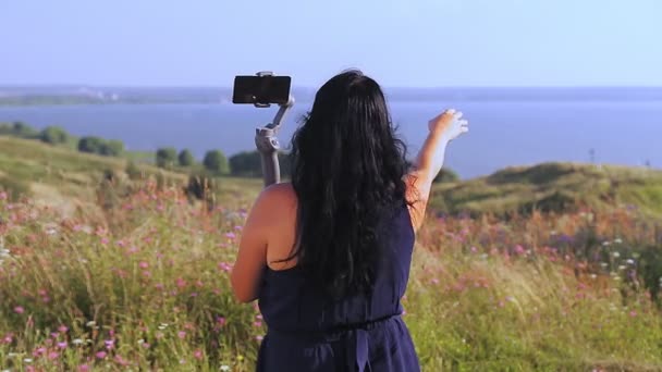 Vrouwelijke reiziger bloggen vanaf de telefoon vanaf de top van de berg met uitzicht op het meer — Stockvideo