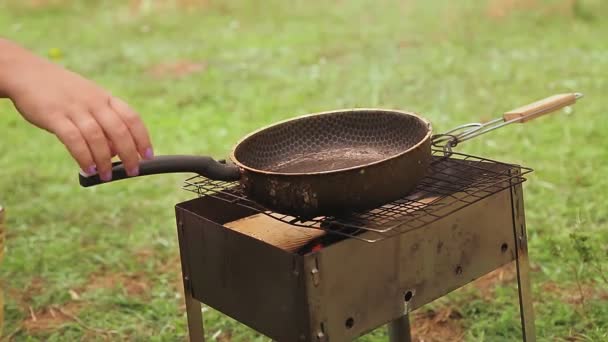 한 여자가 남비에 프라이팬을 얹고 그 안에 야채 기름을 붓는다 — 비디오
