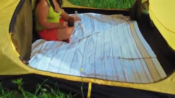 Une femme dans une tente dans une clairière verte boit du thé — Video