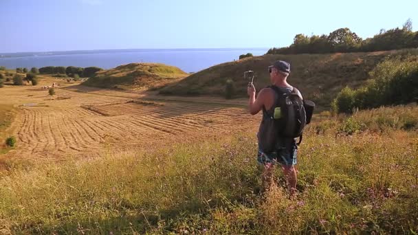 Egy férfi utazó blogol egy mobiltelefonról a hegy tetejéről. — Stock videók