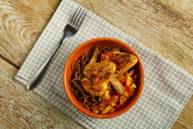 Sebzeli soba şehriyeli kahve fincanı peçeteli tavuk kanadı ve yakınlarda bir çatal. Yatay fotoğraf