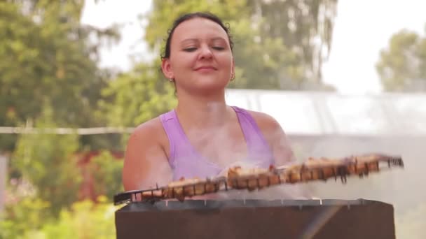 Een vrouw roostert vlees in de tuin van haar huis — Stockvideo