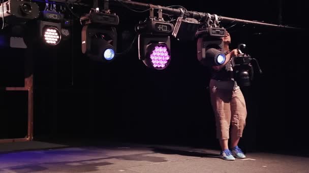 Eine Strahlerin hängt einen Scheinwerfer an einen Mast mit Beleuchtungskörpern — Stockvideo