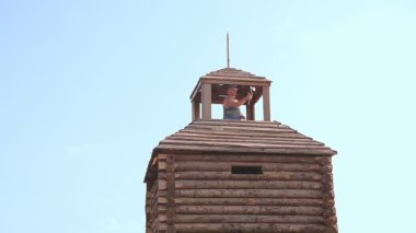 Bir erkek blogcu kaledeki gözlem güvertesinden telefonundan blog yazıyor..