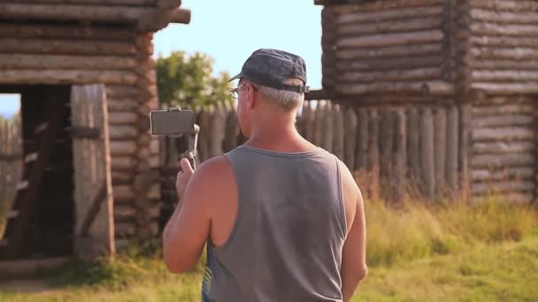 Ένας άντρας blogger γράφει στο κινητό του και μιλάει για ένα ξύλινο φρούριο — Αρχείο Βίντεο