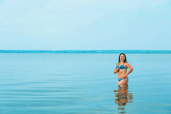 海岸近くの紺碧の水の中で夜明けに水着のブルネットの女性. — ストック写真