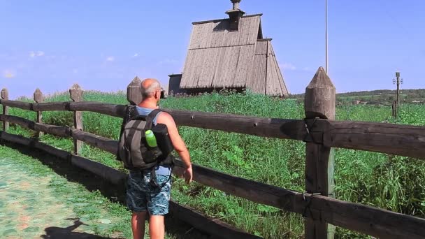 Un blogger masculino está transmitiendo desde la cima de una montaña hablando de un templo de madera — Vídeo de stock