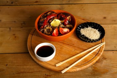 Soba, tavuklu ve sebzeli. Yuvarlak bir tabakta, soya sosu ve susam tohumlarıyla..