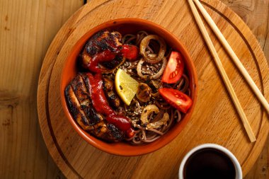 Tavuk ve sebzeli soya soslu soba ve çubukların yanında susam tohumu..