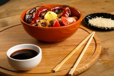 Soba, tavuk ve sebzeyle birlikte soya sosu ve susam tohumlarıyla dolu yuvarlak bir büfede..