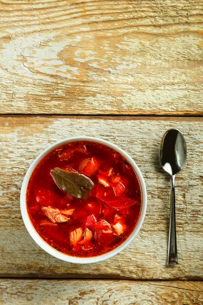 Un piatto di borscht con pollo e un cucchiaio vicino su un tavolo di legno. — Foto Stock