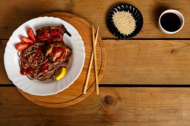 Yuvarlak bir tezgahta tavuklu soya sosu ve yemek çubuklarının yanındaki susam tohumlarıyla birlikte soba.