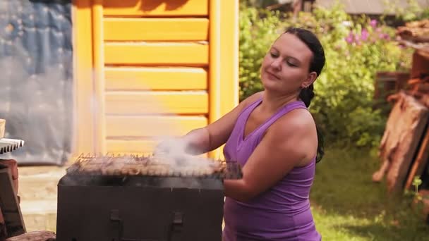 Una mujer asa carne en el patio de su casa. — Vídeos de Stock