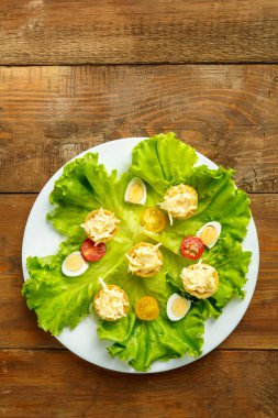 Tahta bir masada bıldırcın yumurtası salatasıyla tabakta peynir ve sarımsaklı turta..