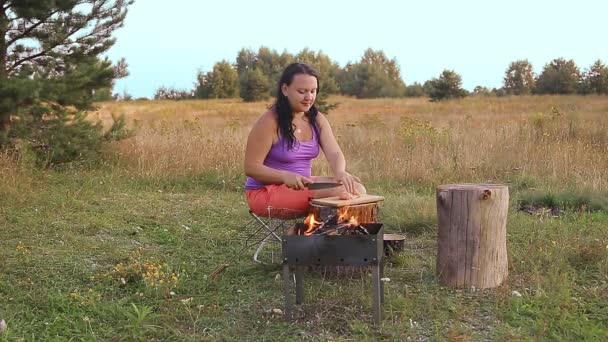 一个晚上在火边的黑发女人在木板上切鸡肉烧烤 — 图库视频影像