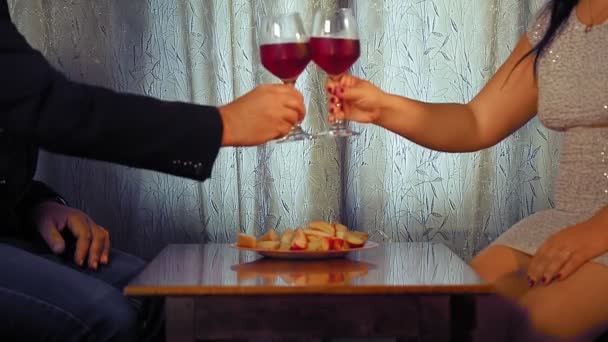 Un hombre y una mujer sin rostro celebran la cita en la mesa y beben vino tinto. — Vídeos de Stock