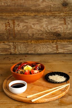 Yuvarlak bir tezgahta tavuklu soya sosu ve yemek çubuklarının yanındaki susam tohumlarıyla birlikte soba.