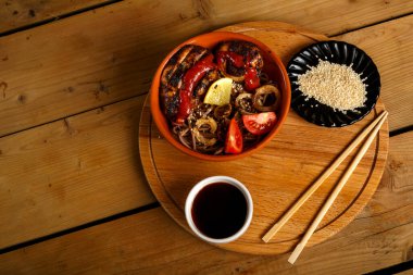 Yuvarlak bir büfede tavuklu soya sosu ve çubukların yanında susam tohumlu soba..