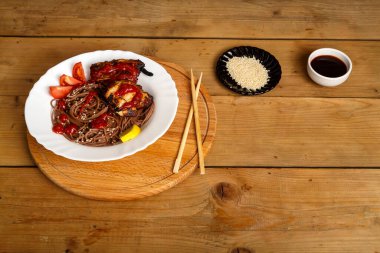 Yuvarlak bir tezgahta tavuklu soya sosu ve yemek çubuklarının yanındaki susam tohumlarıyla birlikte soba.